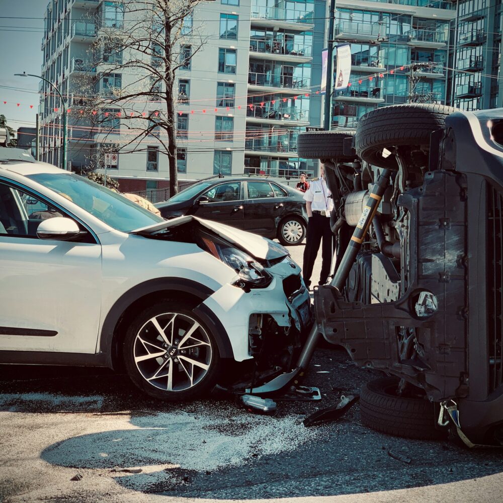 car accidents An overturned car lies on its side beside the road, indicating a recent accident or emergency situation.